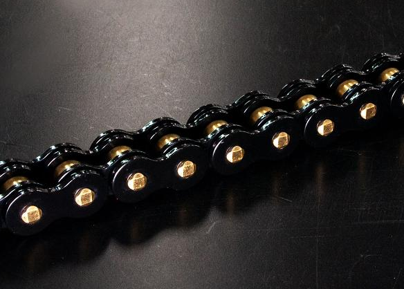 Close-up of a black metal bicycle chain with visible circular pins on a dark surface.